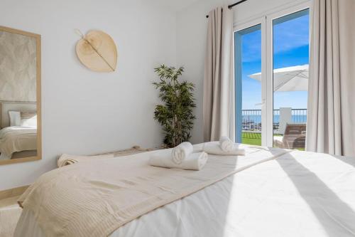 a white bedroom with a bed and a large window at Luxury family apartment with breathtaking views in Marbella