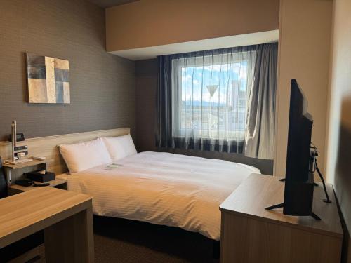a hotel room with a bed and a window at Hotel Route Inn Ginan -Kokudo 21 Gou- in Ginan