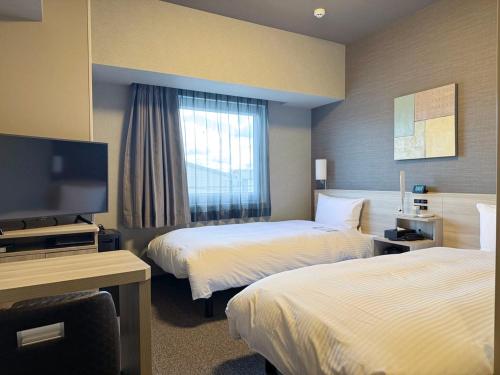 a hotel room with two beds and a flat screen tv at Hotel Route Inn Ginan -Kokudo 21 Gou- in Ginan