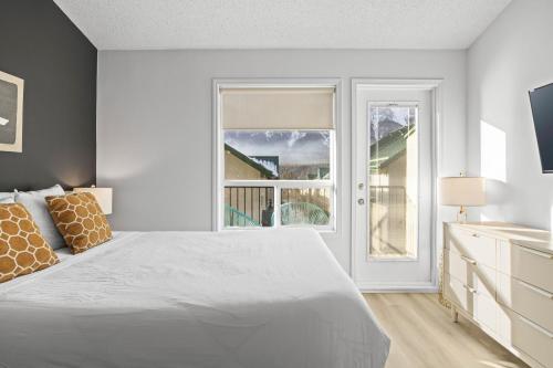 a white bedroom with a large bed and a window at B233 Mountain View 2BD 2BT AC BonFire BBQ Townhome Close to Banff in Canmore