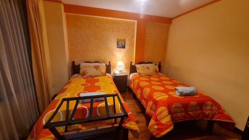 a bedroom with two beds with orange sheets at Hostal Montañes in La Paz