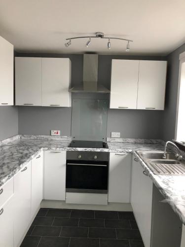 a kitchen with white cabinets and a black dishwasher at Spacious 2 bedroom apartment, entire place in Greenock