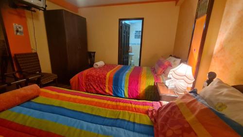 a room with two beds with colorful blankets at Hostal Montañes in La Paz