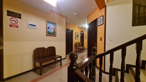 a hallway with a staircase with a chair and signs on the wall at Hostal Montañes in La Paz