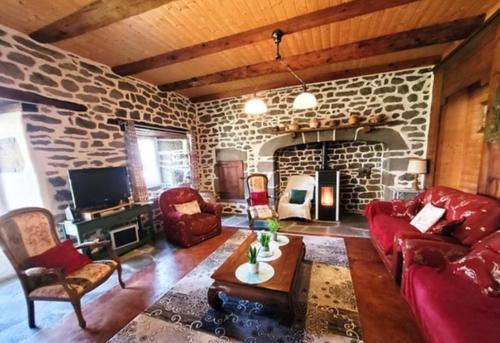 sala de estar con chimenea de piedra y muebles de color rojo en Gîte Le Parsou, en Cussac