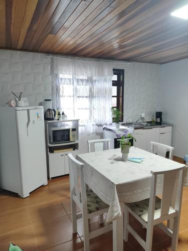 a kitchen with a white table and a white refrigerator at Residência Vô José - Casa 02 in Pomerode