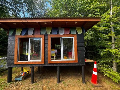 a small house with awning and windows in a forest at Ruka Rayen in Quepe