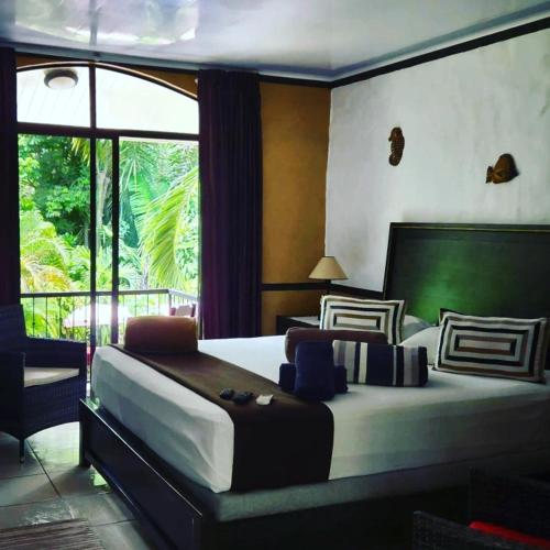a bedroom with a large bed and a large window at Hotel Belvedere Playa Samara Costa Rica in Sámara