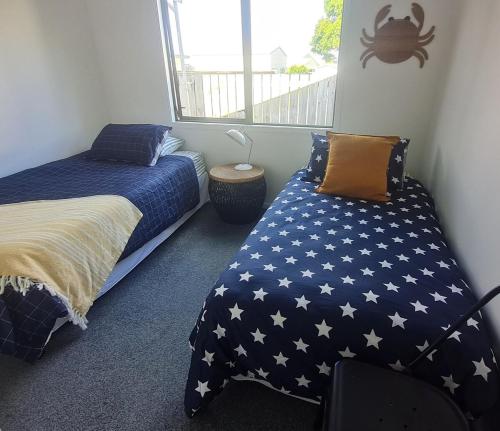 two beds in a room with an american flag blanket at The Kraken Cottage in Whitianga