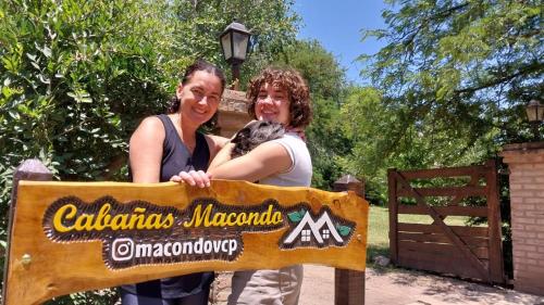 two women standing behind a sign at a zoo at Cabañas MACONDO in Villa Ciudad Parque