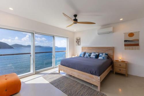 a bedroom with a bed and a large window at Cannon Point Estate in Cane Garden Bay