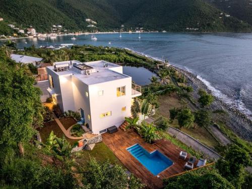 an aerial view of a house next to the water at Cannon Point Estate in Cane Garden Bay