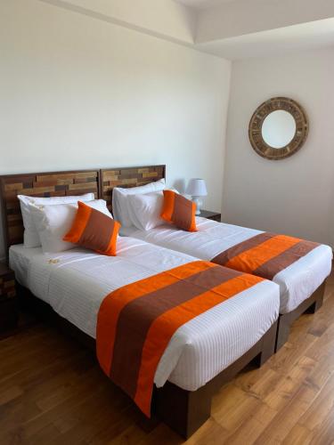 a bedroom with two beds with orange and white pillows at Luxury penthouse , Nilaveli, Srilanka in Nilaveli