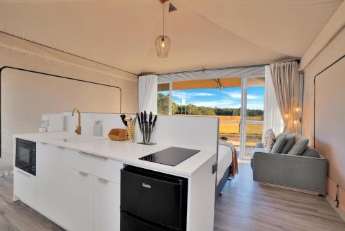 a kitchen with a white counter top and a couch at The Beltree Wine Country Glamping in Belford