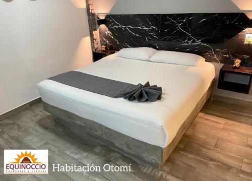 a bed with a black bow on top of it at Posada Equinoccio in Bernal