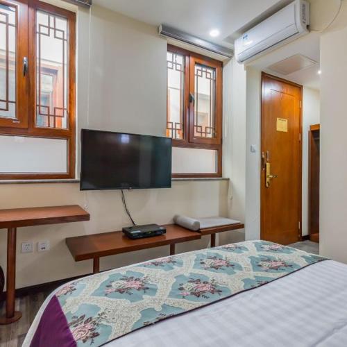 a bedroom with a bed and a flat screen tv at The Qomolangma Hotel Beijing China in Beijing