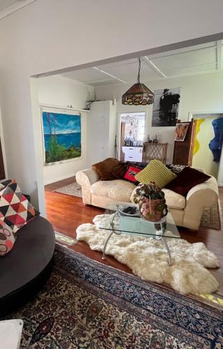 a living room with two couches and a table at Unique city bungalow in Whangarei