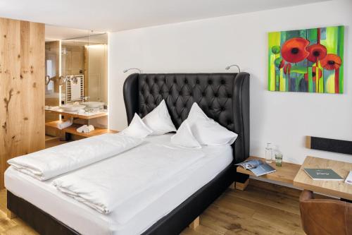 1 dormitorio con 1 cama blanca grande y cabecero negro en Fritsch am Berg - Adults only, en Lochau