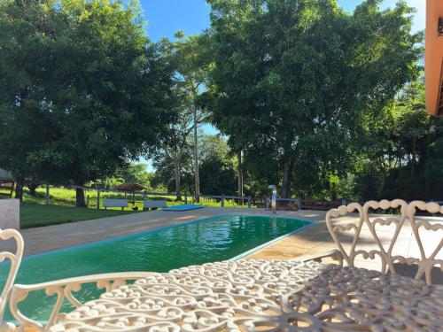a pool with two chairs and a table next to it at Sítio Canto da Seriema in Torrinha