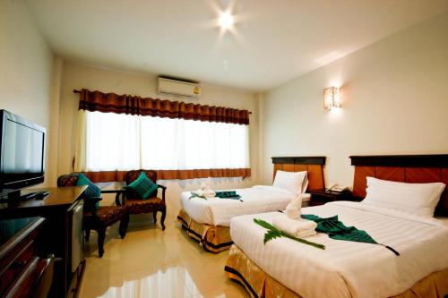 um quarto de hotel com duas camas e uma televisão de ecrã plano em Chiangrai Grand Room Hotel em Chiang Rai