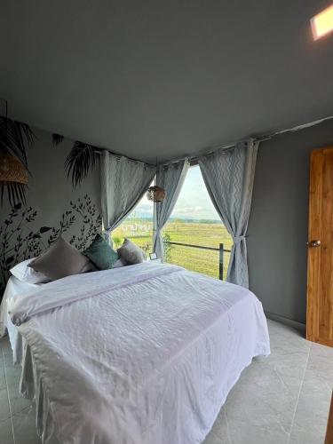 Un dormitorio con una cama blanca con una ventana. en นาน้าหมูฟาร์มสเตย์ NanamooFarmStay, en Trang