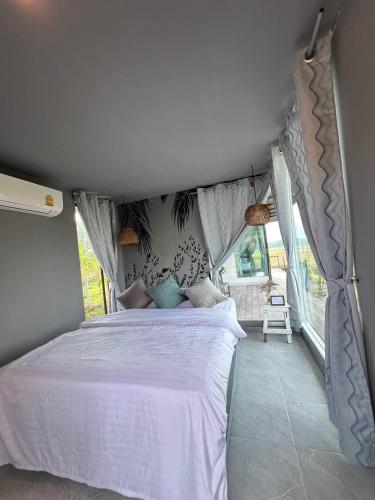 a bedroom with a white bed in a room at นาน้าหมูฟาร์มสเตย์ NanamooFarmStay in Trang