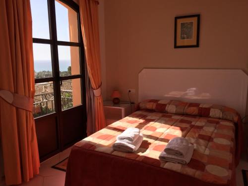 a bed with a blanket and pillows in front of a window at Apartamentos El Toro in Marbella