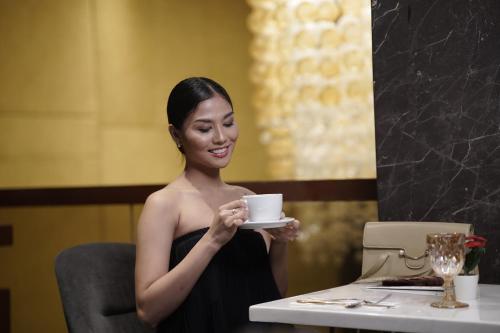 a woman sitting at a table holding a coffee cup at Villa Isabel Hotel in Sorsogon