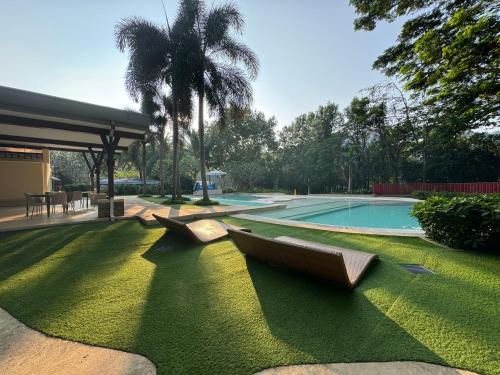 a swimming pool with two boats on the grass at Sunset Room at Pico - Hamilo Coast Pico De Loro in Nasugbu