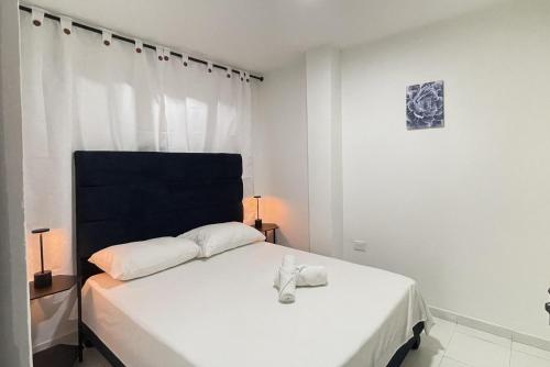 カリにあるApartamentos Sur de Cali Amplios bien ubicadosのベッドルーム(白いベッド、黒いヘッドボード付)