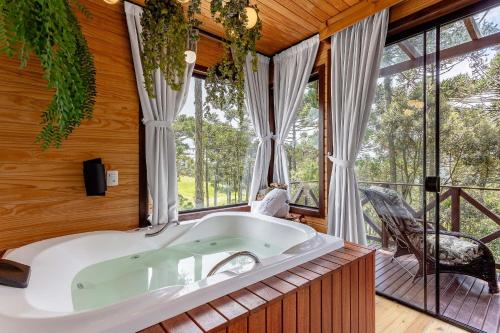 una vasca da bagno in una stanza con finestre di Chalé O Canto da Araponga a Águas Brancas