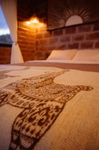 a blanket with a cross on a bed at Yaktari Cabaña del Sol in Otavalo