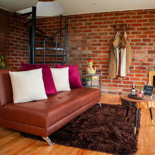a brown couch in a room with a brick wall at Yaktari Cabaña del Sol in Otavalo