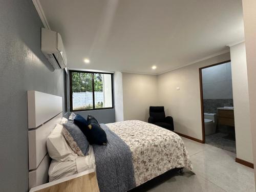 a bedroom with a bed and a window and a bathroom at Casa Marigold in Coyol