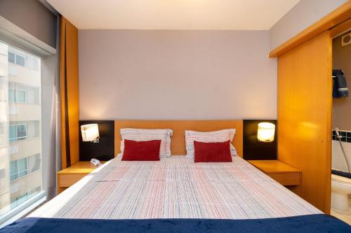 a bedroom with a bed with two red pillows at LFlats no Hotel Stella Vega (EX-Mercury Ibirapuera) in Sao Paulo