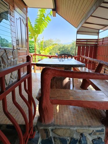 a patio with a table and benches on a building at บ้านไร่ภูวังน้ำ in Ban Khlong Ki