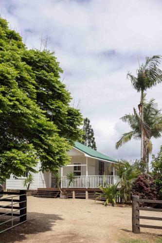 a white house with a fence and palm trees at Black Cockatoo Bangalow in Binna Burra