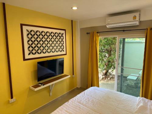 a bedroom with a bed and a tv and a window at Mem Homestay in Ban Khlong Wang Chang