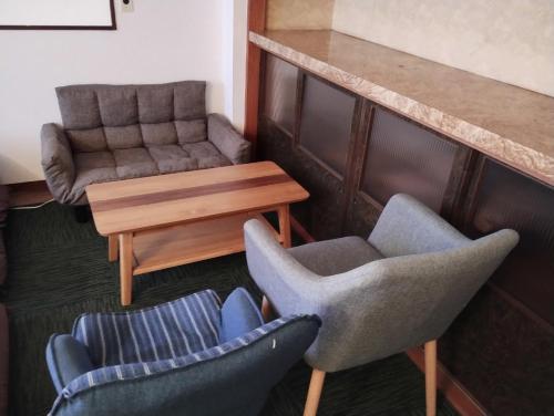 a living room with two chairs and a table and a couch at Backpackers Kur Guesthouse Asahirou 旅人湯治客舎朝日楼 in Kaga