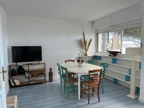 une salle à manger avec une table et des chaises et une télévision dans l'établissement Appartement T3 en bord de mer avec parking sécurisé et WiFi - FR-1-374-230, à Arcachon