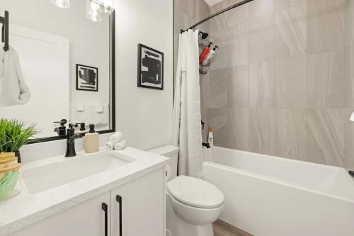 a white bathroom with a toilet and a tub and a sink at Cozy Saanich Cottage ideal location to UVIC and Downtown in Victoria