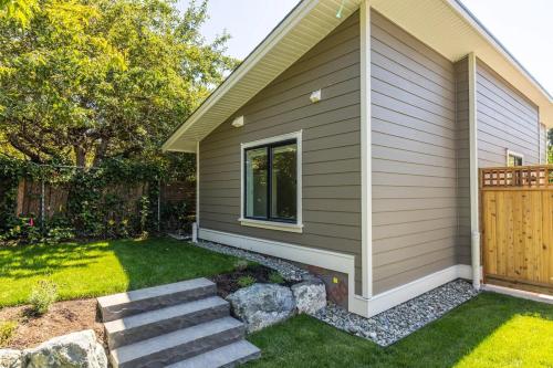 a home with a yard with stairs next to a house at Cozy Saanich Cottage ideal location to UVIC and Downtown in Victoria
