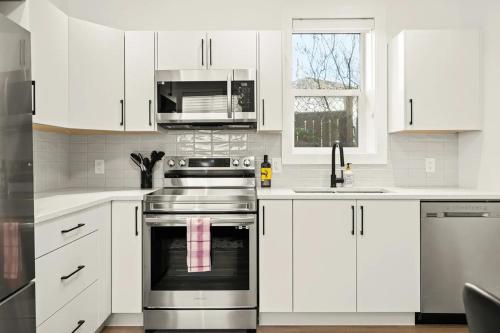 a kitchen with white cabinets and a stainless steel oven at Cozy Saanich Cottage ideal location to UVIC and Downtown in Victoria