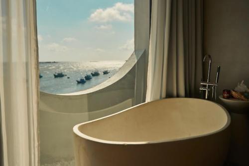 une baignoire dans une salle de bain avec une fenêtre dans l'établissement L'amant Boutiqué House Phú Quý, à Cu Lao Thu