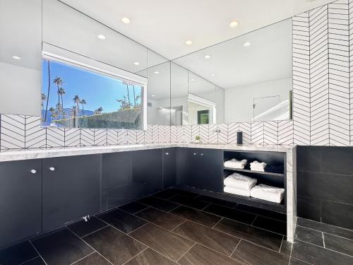 a bathroom with a large mirror and black and white tiles at Villa Caliente in Palm Springs
