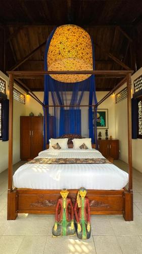 a bedroom with a canopy bed with two pairs of sandals at Villa Borobudur Resort in Borobudur