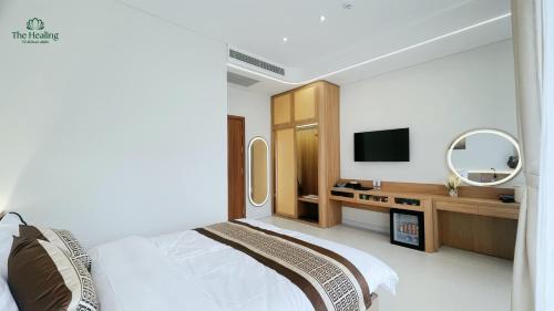 a bedroom with a bed and a desk with a tv at The Healing Luxury Hotel in Buon Ma Thuot