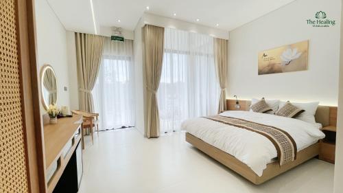 a bedroom with a bed and a desk and windows at The Healing Luxury Hotel in Buon Ma Thuot