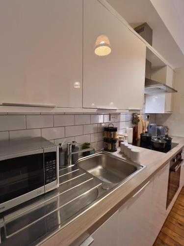 a kitchen with a stainless steel sink and a microwave at CityZenSanctuary - Snug Comfy 2BR Apartment Sleeps 6 Sheffield City Centre in Midland