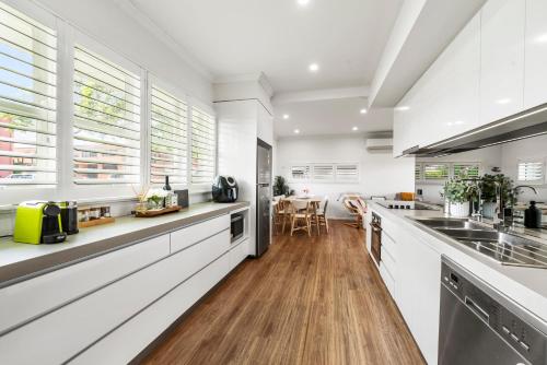 a kitchen with white walls and wooden floors and windows at Boutique Living East Toowoomba in Toowoomba